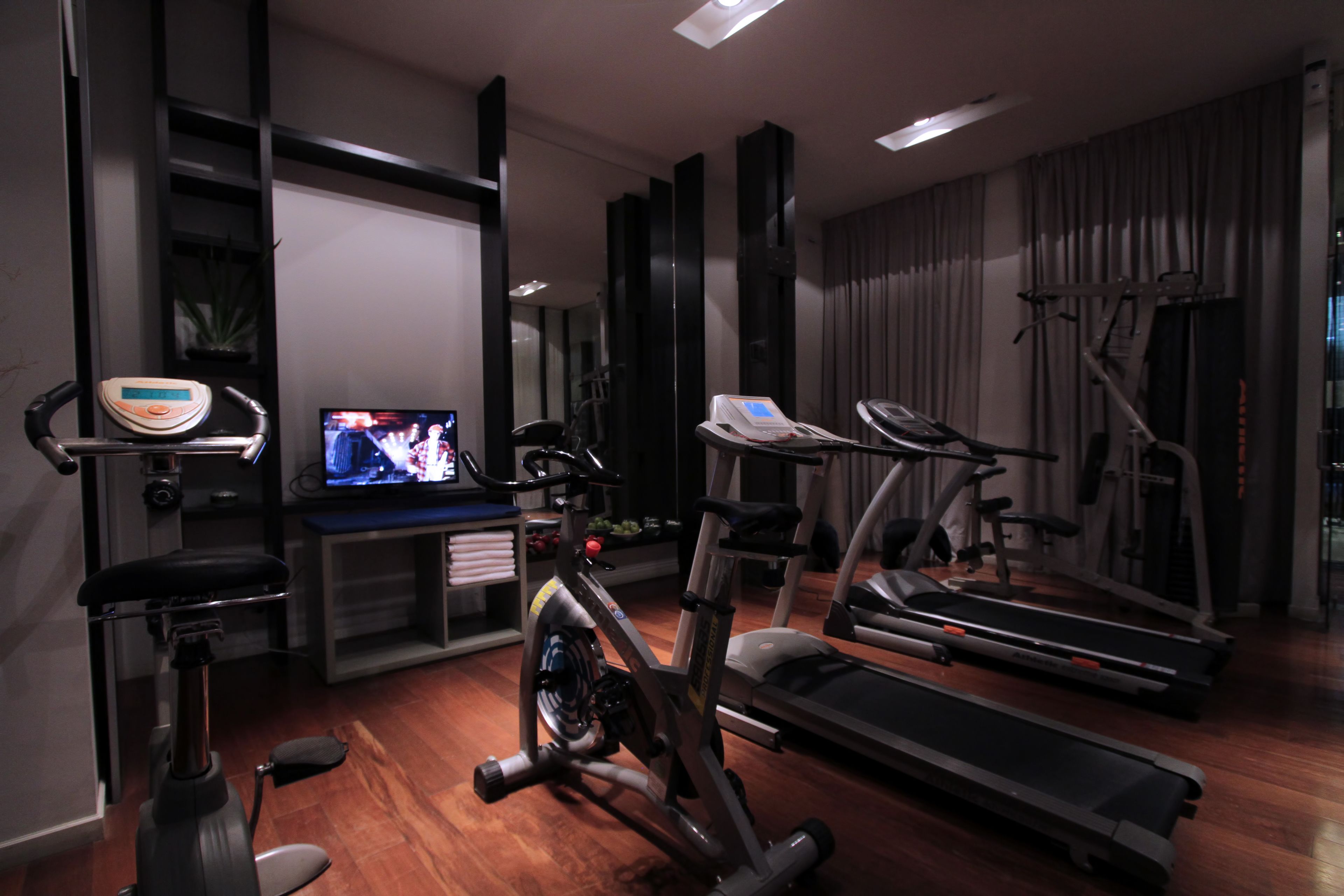 Une salle de sport à domicile équipée d’appareils d’exercice, notamment un vélo d’appartement, un appareil elliptique, un tapis de course et une balance.