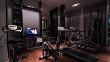 Une salle de sport à domicile équipée d’appareils d’exercice, notamment un vélo d’appartement, un appareil elliptique, un tapis de course et une balance.