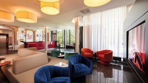 A modern hotel lobby with seating areas, a reception desk, and large windows. - NOVINA HOTEL Tillypark (Nuremberg)