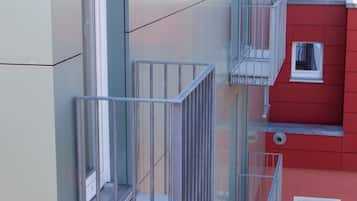 A modern building with a glass balcony and a red facade.