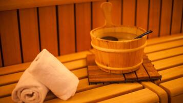 A wooden bench with a rolled white towel and a wooden bucket with a spoon.