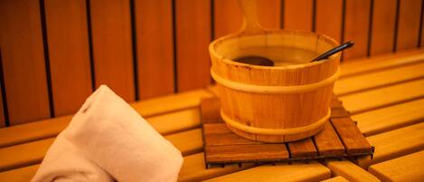 A wooden bench with a rolled white towel and a wooden bucket with a spoon.