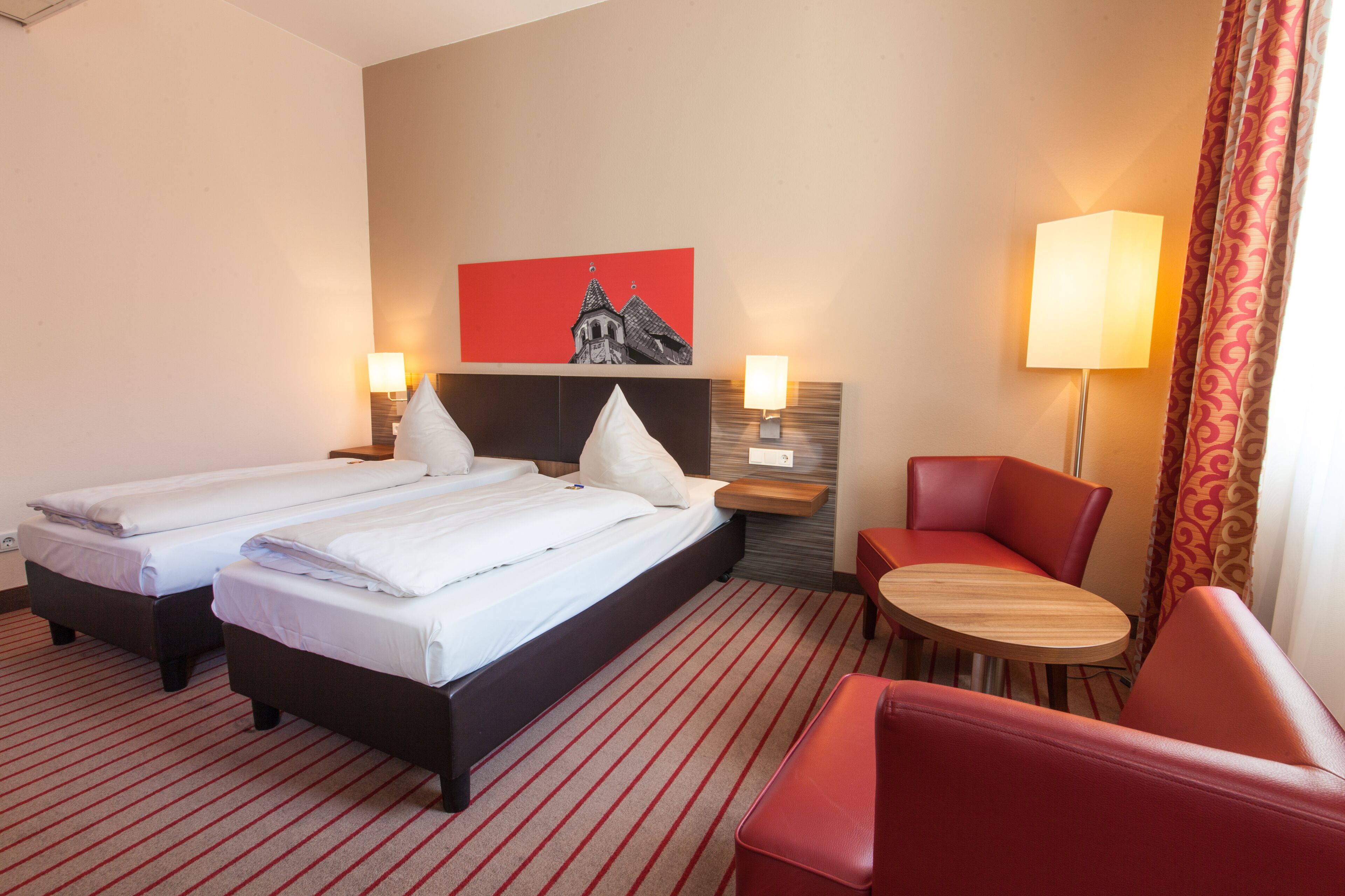 A hotel room with two beds, a desk, and a chair.