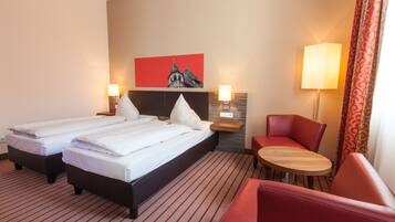 A hotel room with two beds, a desk, and a chair.