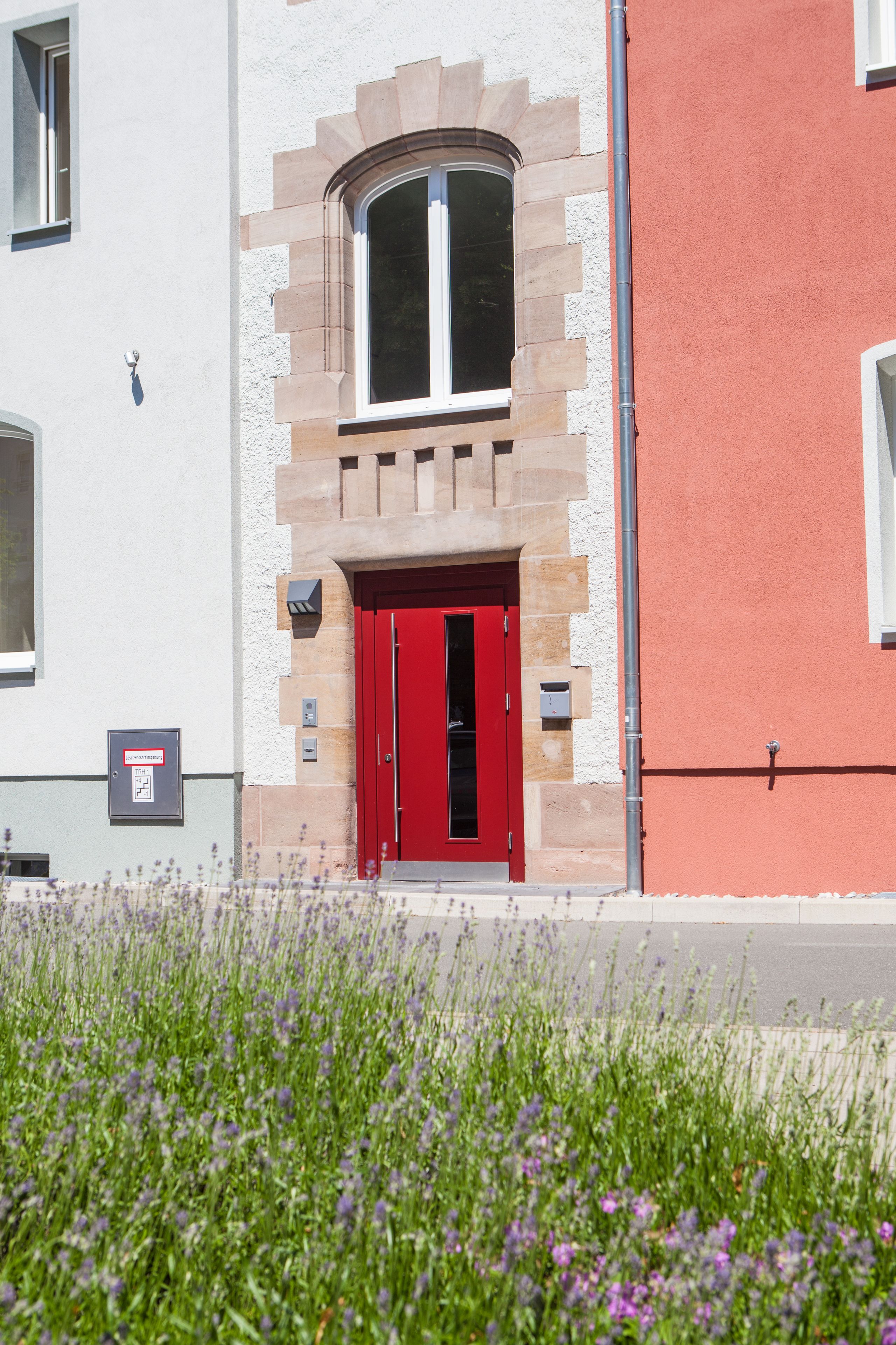 A building with a red door, a stone archway, and a window above the door.