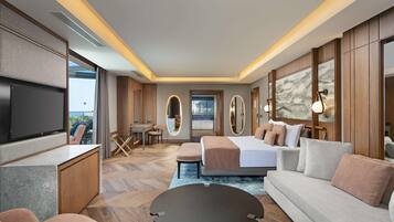 A modern hotel room with a flat-screen TV, a sofa, a bed, a desk, and a large window.