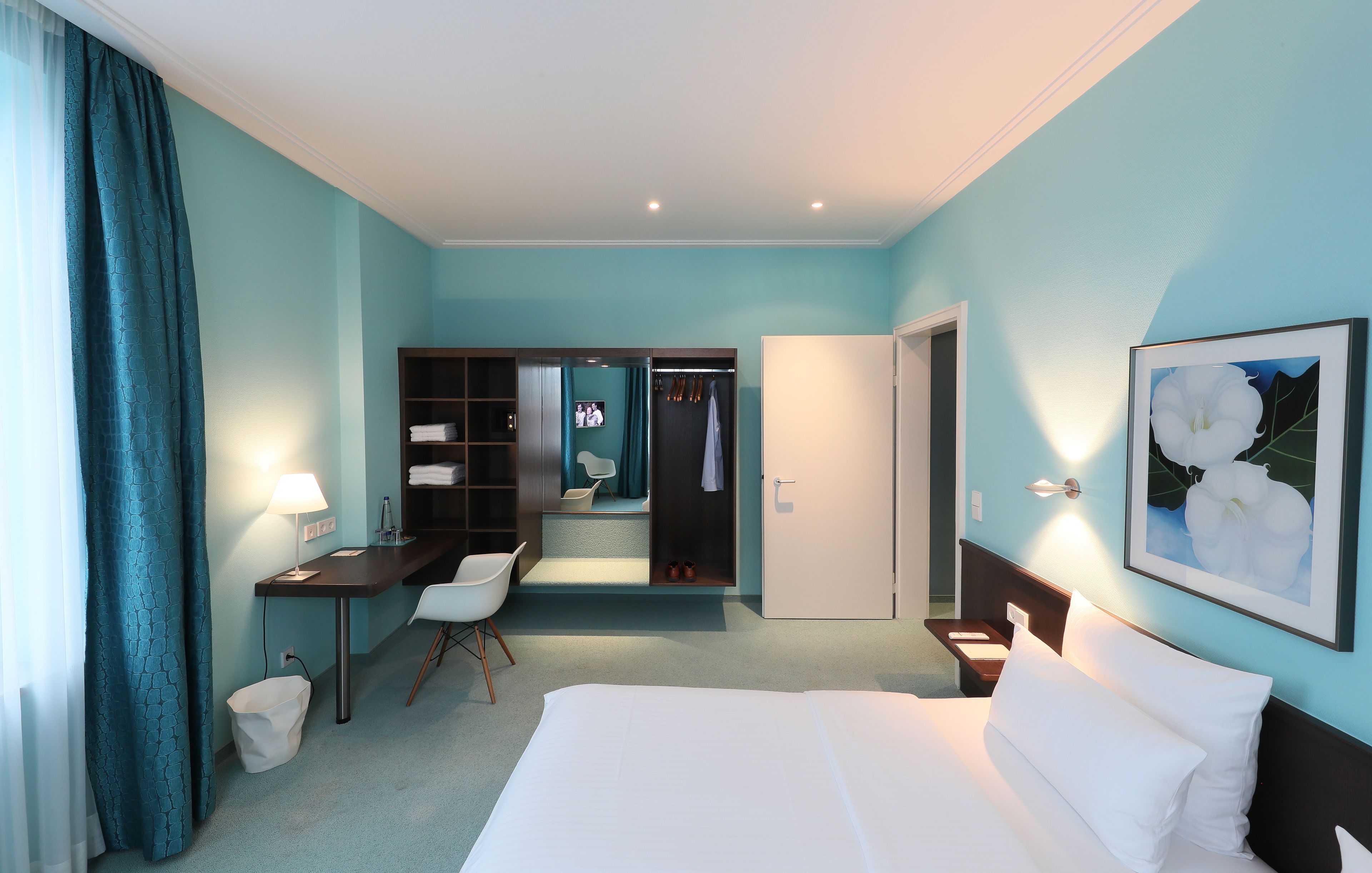 Ein Hotelzimmer mit einem Bett, einem Schreibtisch, einem Stuhl, einem Kleiderschrank und einem Spiegel.