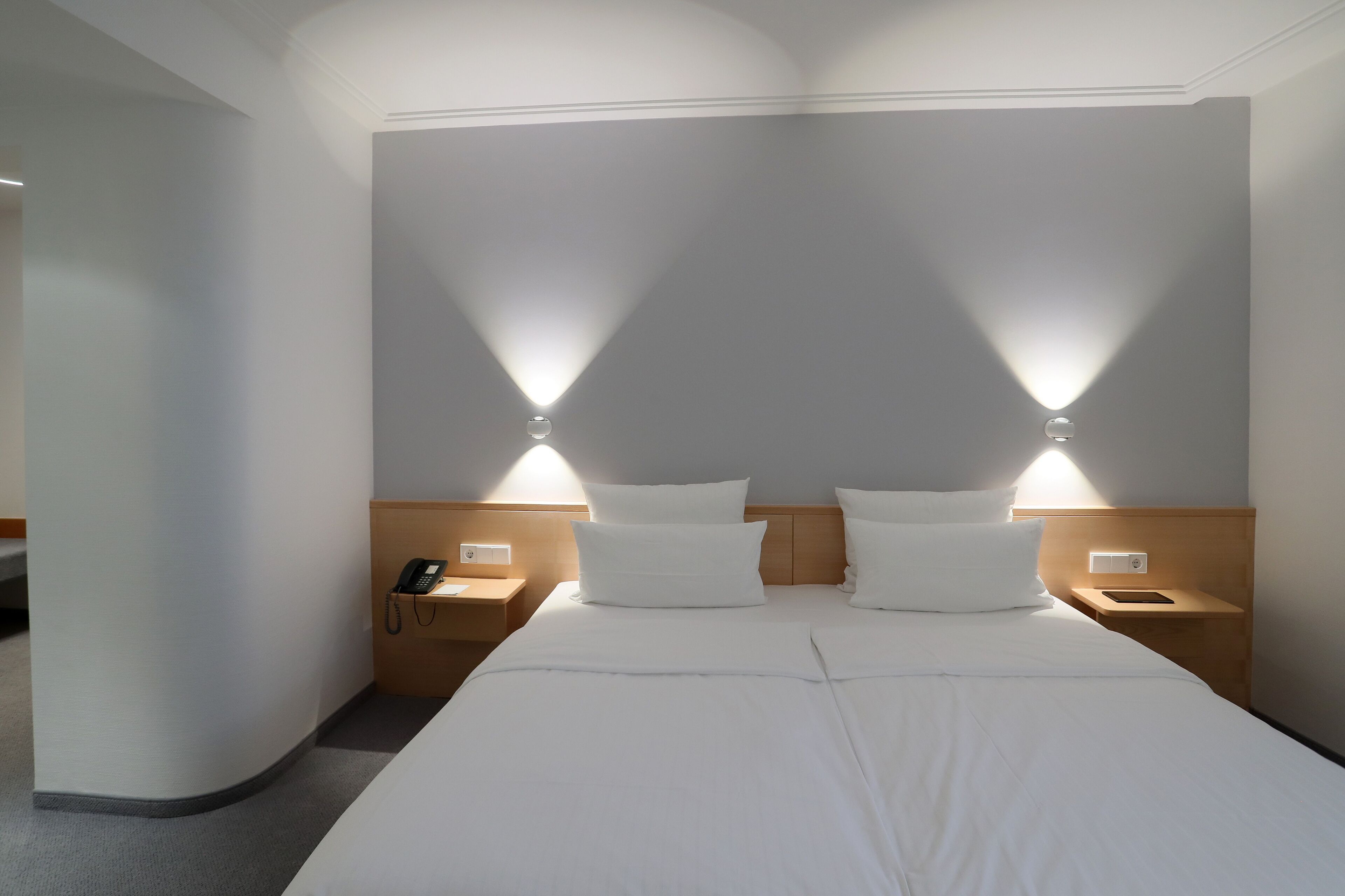 Ein Hotelzimmer mit einem großen Bett, zwei Nachttischen, einer Ablagefläche und zwei Wandleuchten.