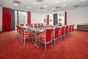 A conference room with a long table, red chairs, and a carpeted floor. - Hotel Münster-Altstadt (Münster)