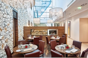 A restaurant with stone walls, wooden tables, and leather chairs. - Hotel Münster-Altstadt (Münster)