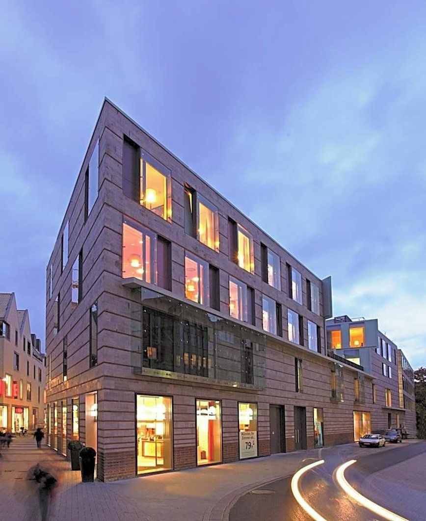 A multi-story hotel with a modern design, featuring large windows and a ground-level entrance.