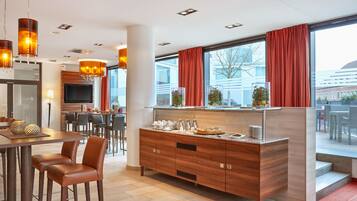 Une cuisine moderne avec un îlot central en bois, des tabourets de bar et une grande fenêtre agrémentée de rideaux rouges.