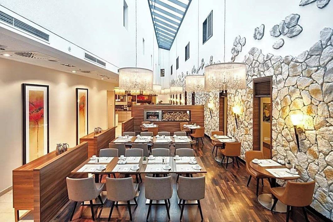 En restaurant med flere spiseområder, stenvægge og moderne lysarmaturer.