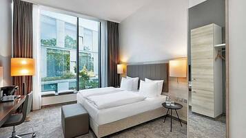 Una habitación de hotel con una cama grande, mesitas de noche, un escritorio y un armario.