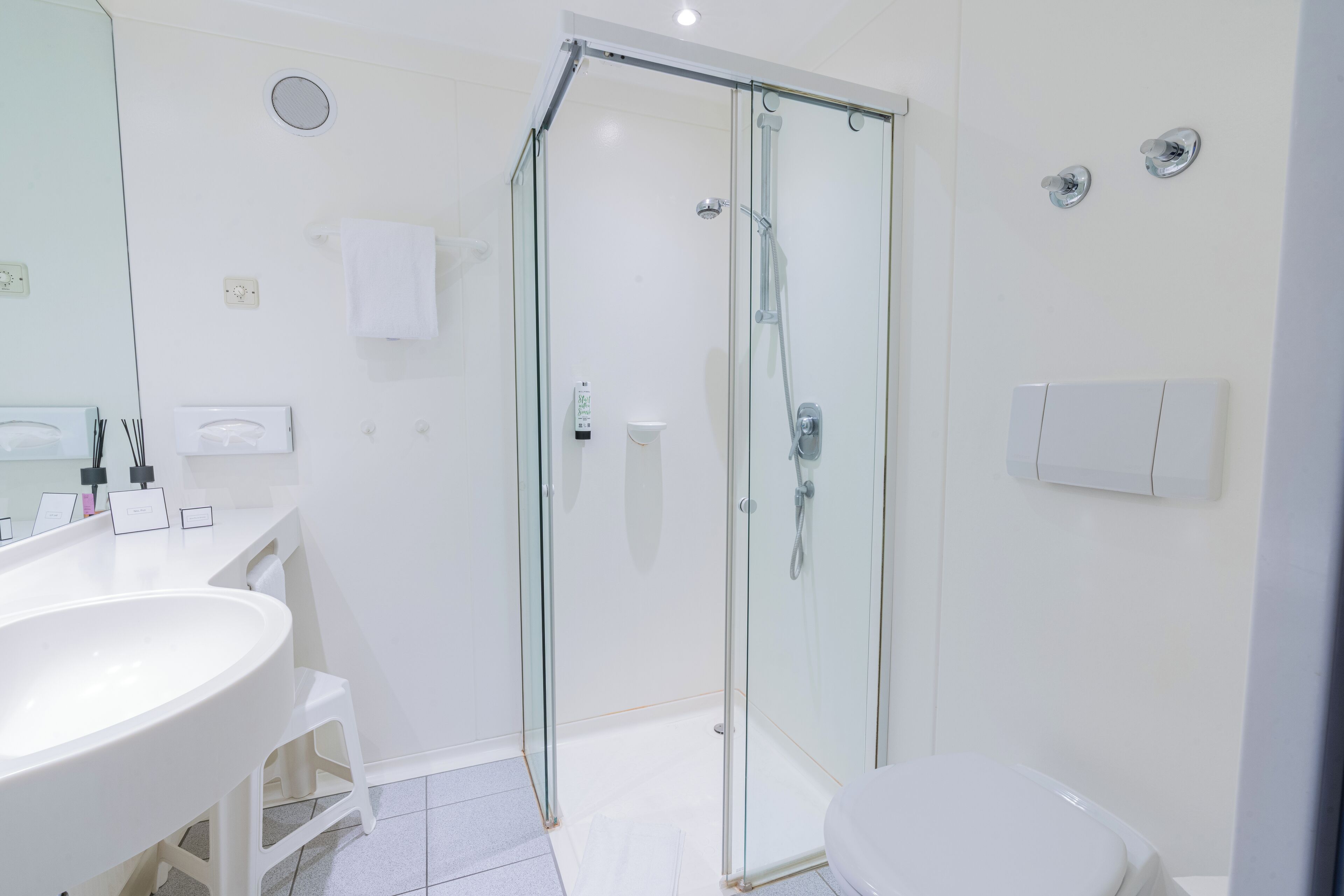 Une salle de bain moderne avec une douche à parois de verre, un lavabo blanc et des toilettes.