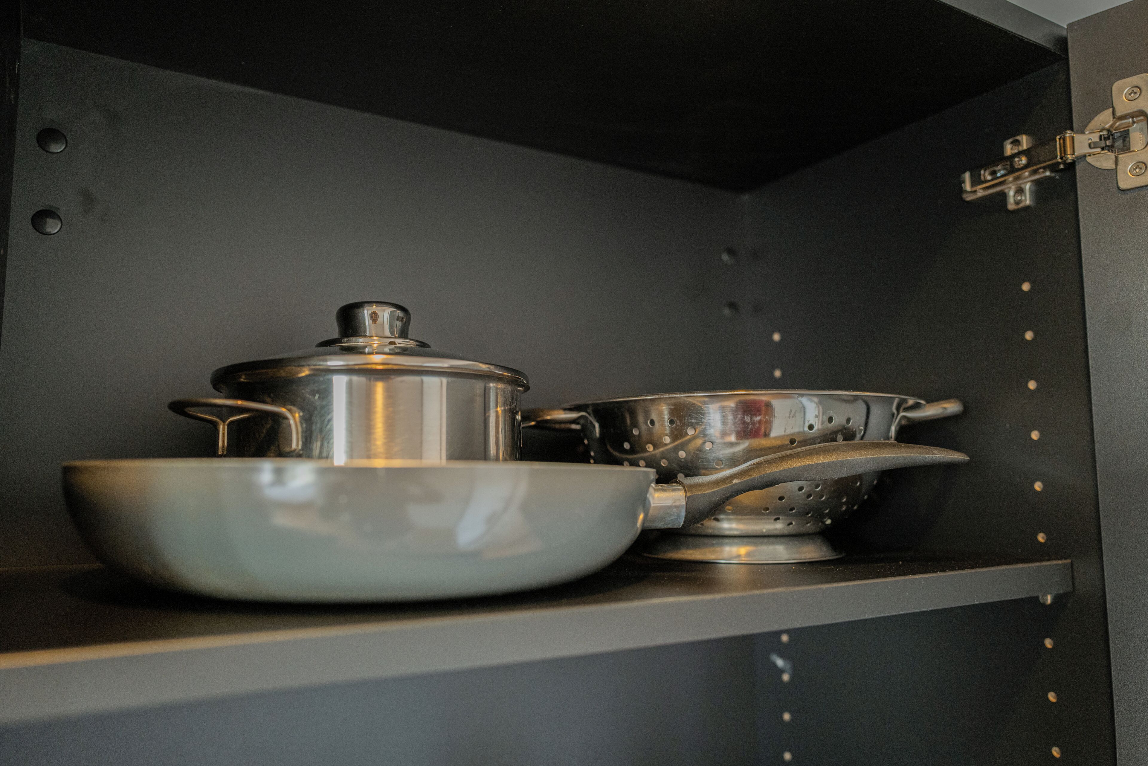 Una cocina con una olla, un bol y un colador sobre una repisa.