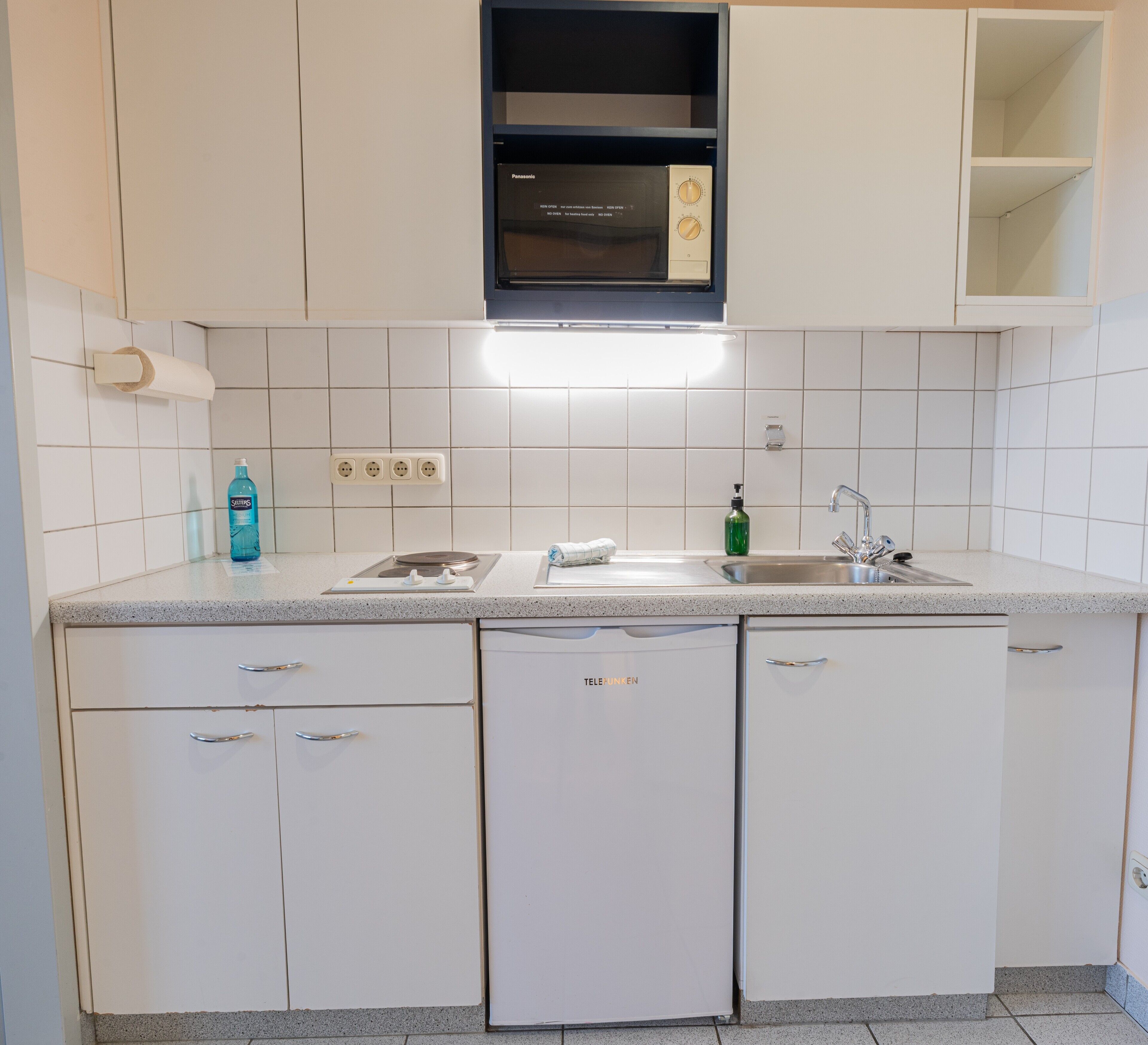 A kitchen with white cabinets, a built-in microwave, a sink, and a dishwasher.