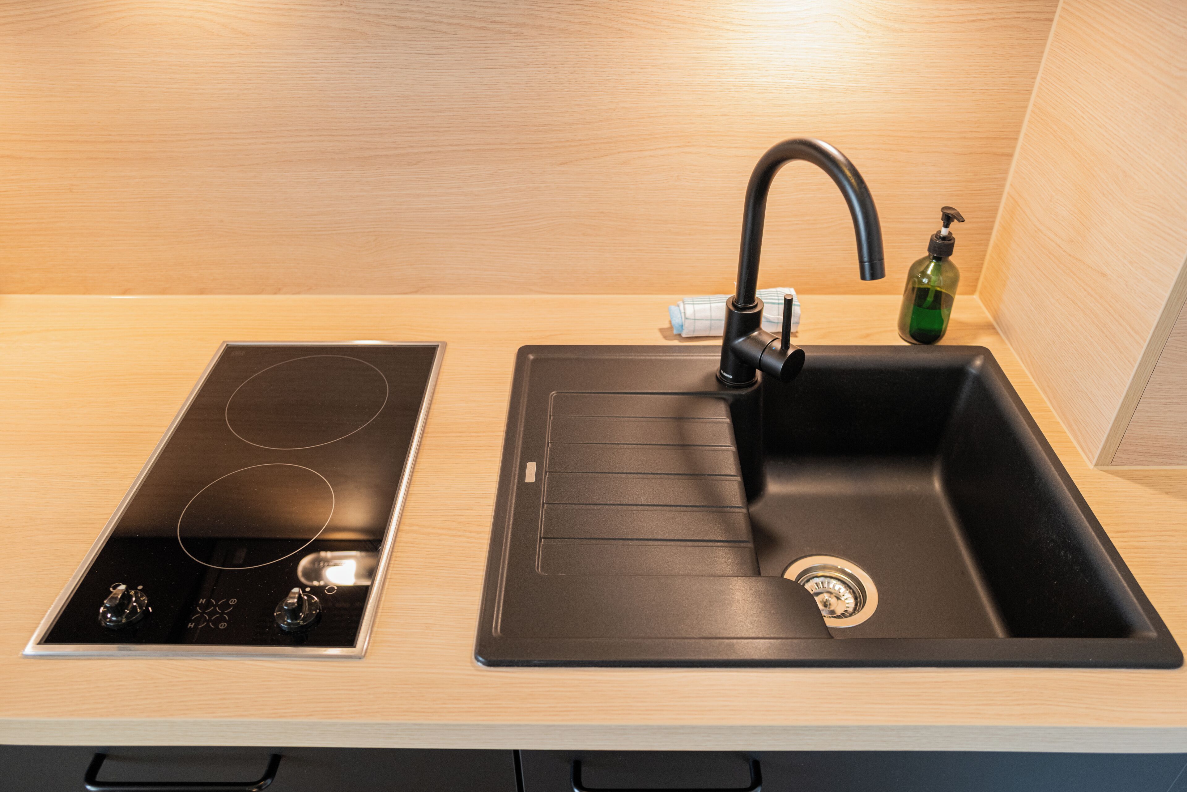 A kitchen with a black sink, a stainless steel stovetop, and a wooden countertop.