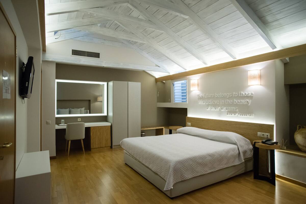 A modern bedroom with a large bed, a desk, and a vanity.