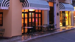 A hotel with a pink facade, multiple balconies, and outdoor seating. - Byzantino Hotel Patras (Patras)