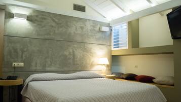 A bedroom with a bed, bedside table, lamp, and a TV mounted on the wall.