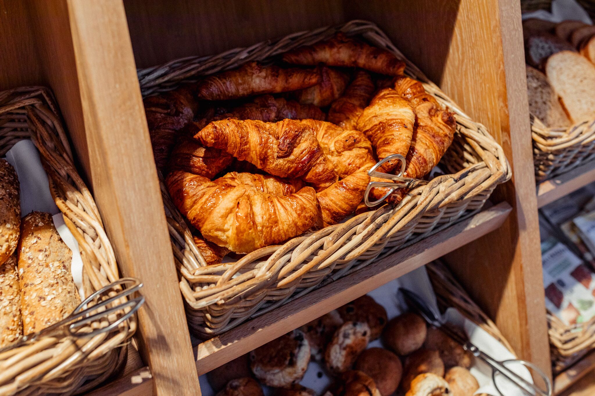 A display of various baked goods, including croissants and bread, arranged in wicker baskets.
