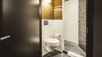 Un bagno con il water, un portasciugamani e una zona doccia.