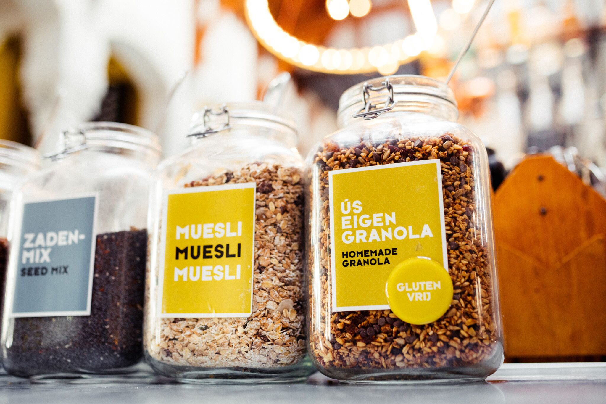 Three glass jars labeled with different types of granola, including gluten-free option.