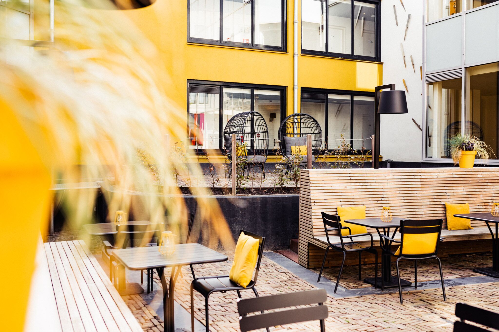 An outdoor seating area with tables and chairs, a wooden bench, and a potted plant.