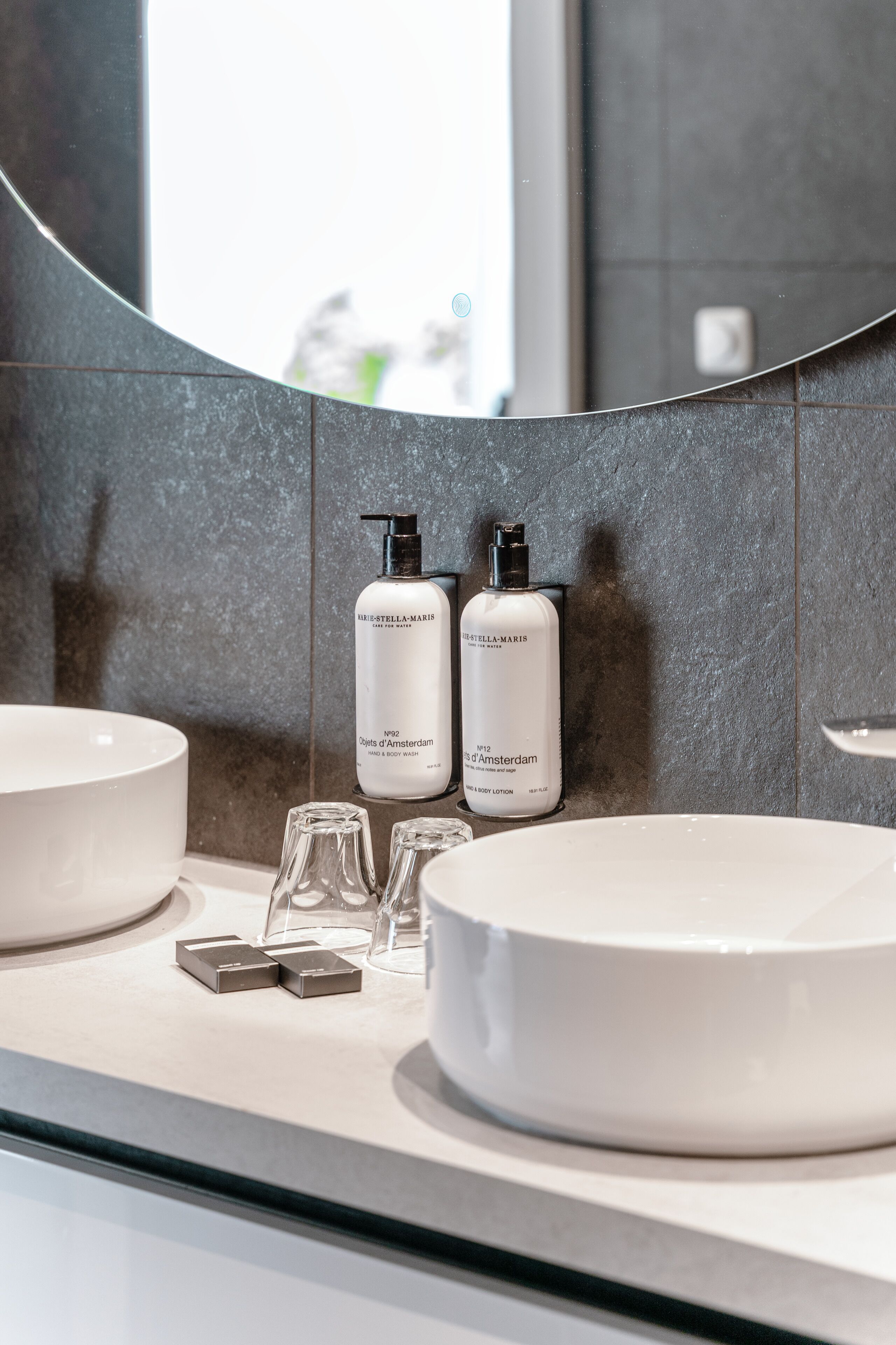 Un baño moderno con dos lavamanos, un espejo grande y dos botellas de loción Stella Maris.