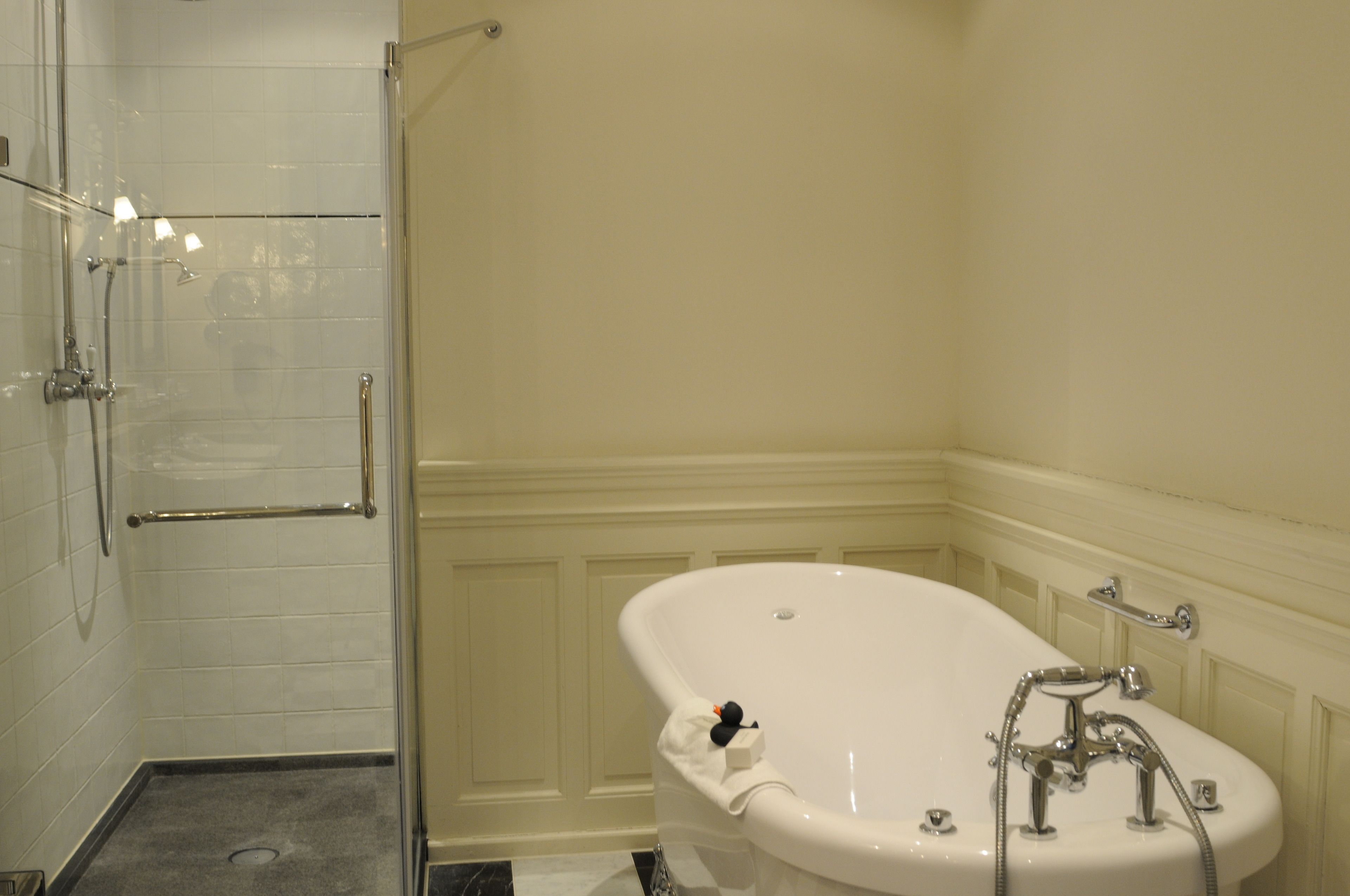 A bathroom with a glass-enclosed shower, a freestanding bathtub, and a white sink.