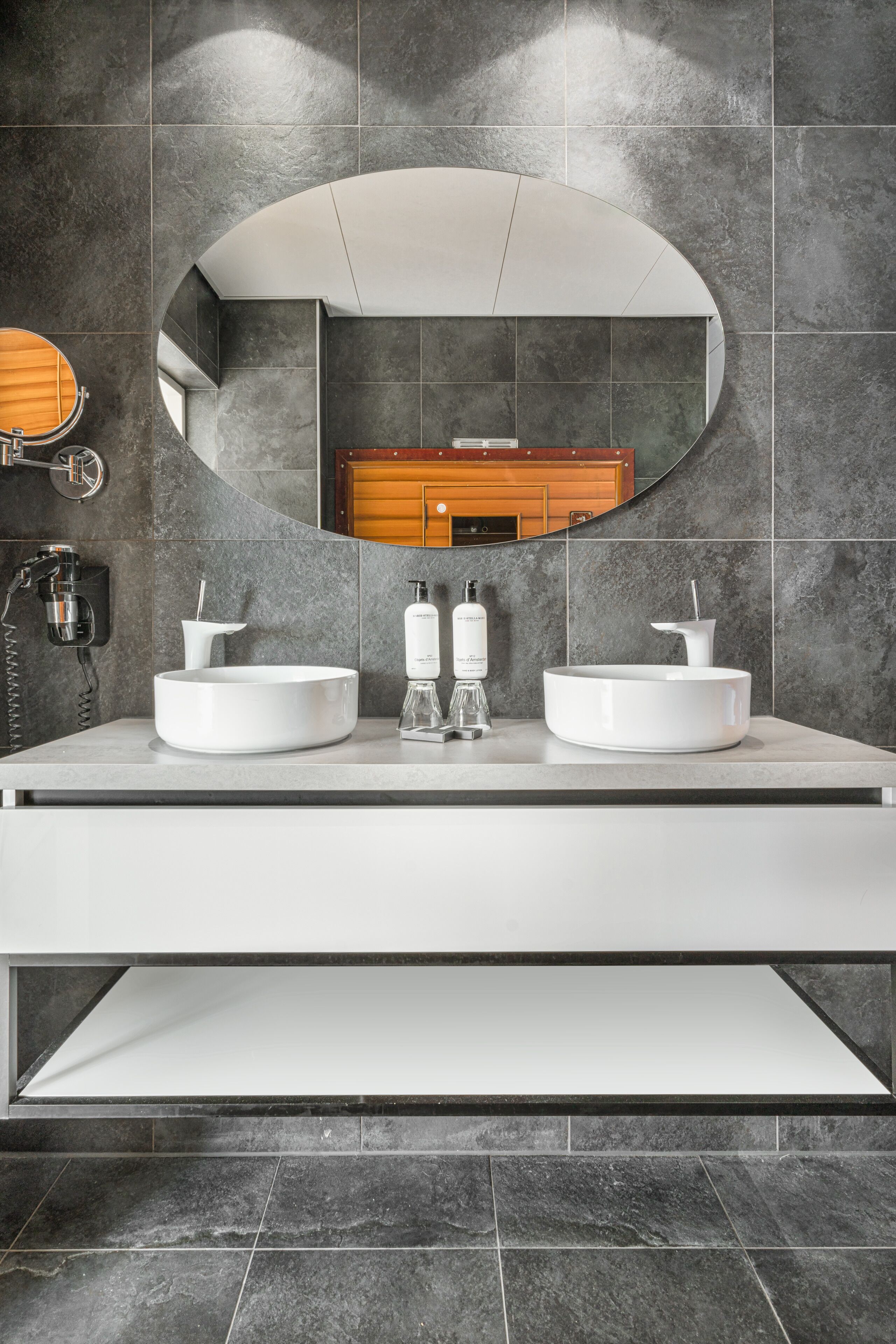 A modern bathroom with a large mirror, two sinks, and a wooden cabinet in the background.