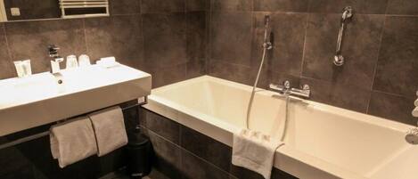 A modern bathroom with a white bathtub, a sink, and a mirror.
