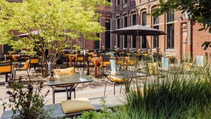 An outdoor patio area with tables and chairs, surrounded by brick buildings and trees. - Post-Plaza Hotel & Grand Café (Leeuwarden)