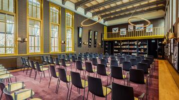 Un vaste hall doté de rangées de chaises, de grandes fenêtres et d’une mezzanine où se trouvent des étagères à livres.