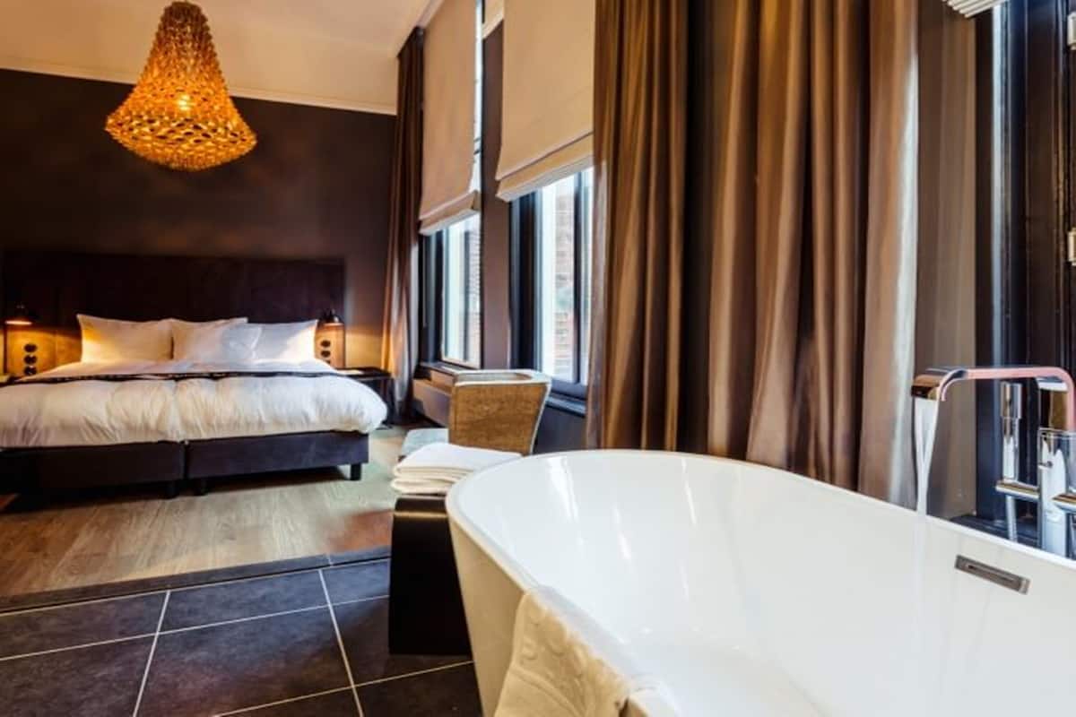 Ein modernes Schlafzimmer mit einem großen Bett, einer Badewanne und einem Kronleuchter.