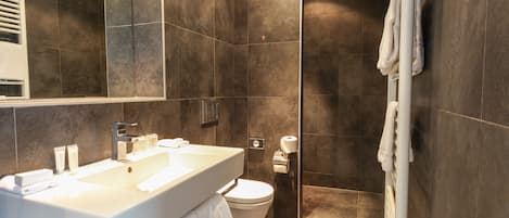 Un baño moderno con un lavamanos grande, inodoro y zona de ducha.