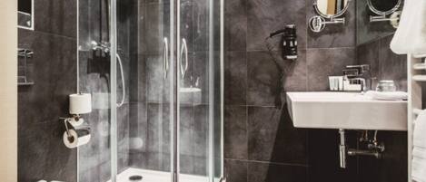 Une salle de bain moderne avec une douche à parois de verre, un lavabo blanc et un miroir.