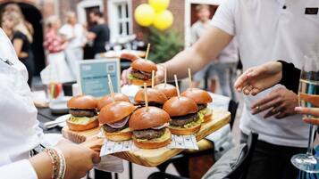 Een houten serveerplank met verschillende burgers, elk vastgeprikt met een cocktailprikker.