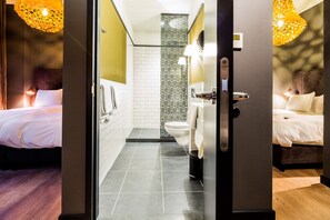 Une chambre d’hôtel comprenant un lit, une salle de bain avec des toilettes et un lavabo, ainsi qu’une douche.