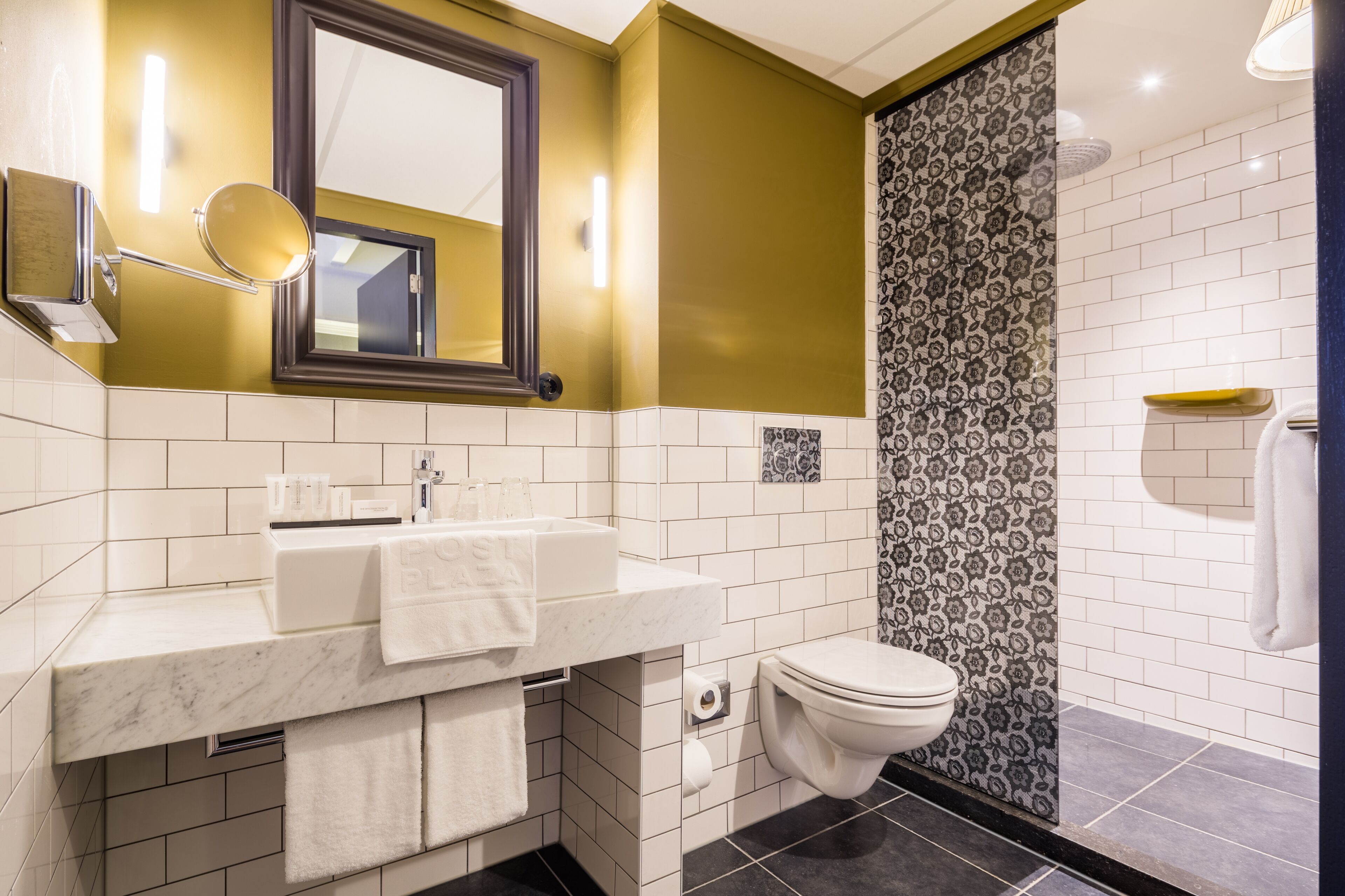 A bathroom with a white sink, a mirror, a toilet, and a shower area.
