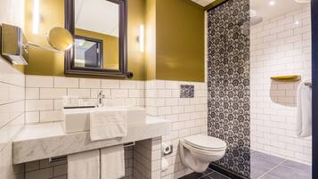 A bathroom with a white sink, a mirror, a toilet, and a shower area.