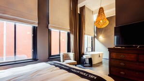 A modern hotel room with a large bed, a TV, a chair, a small table, and a bathtub. - Post-Plaza Hotel & Grand Café (Leeuwarden)