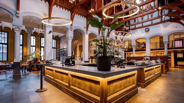 A spacious lobby with a central bar area, high ceilings with exposed beams, and large windows allowing natural light. - Post-Plaza Hotel & Grand Café (Leeuwarden)