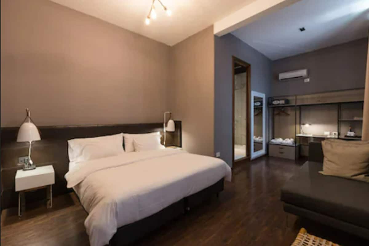 A modern hotel room with a large bed, bedside tables, a sofa, and a wardrobe.