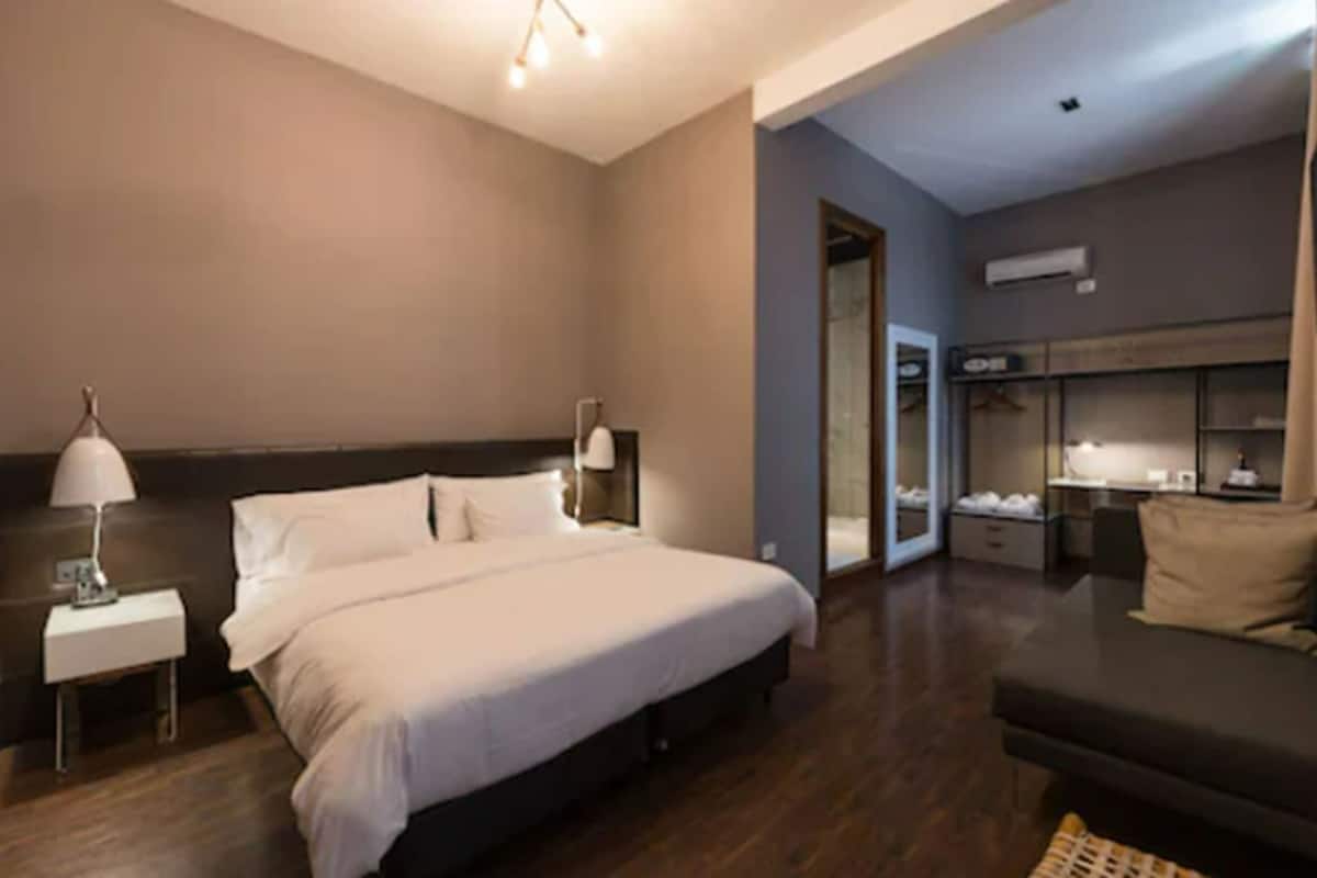 A hotel room with a large bed, a nightstand, a desk, and a seating area.