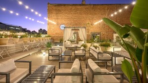 An outdoor seating area with cushioned chairs and tables, surrounded by potted plants and a brick wall. - Azur Real Hotel Boutique & Spa (Córdoba)