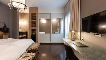 Habitación de hotel con cama, escritorio, televisión y espejo.