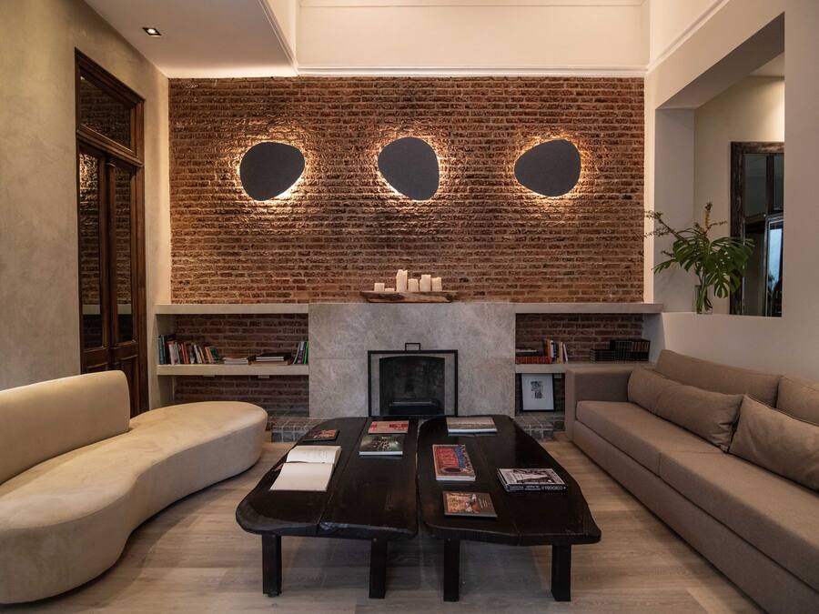 Una sala de estar moderna con pared de ladrillo, chimenea, sofá, una mesa de centro y estanterías.