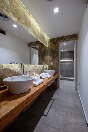 A modern bathroom with a large stone sink, a wooden vanity, and a glass shower enclosure.